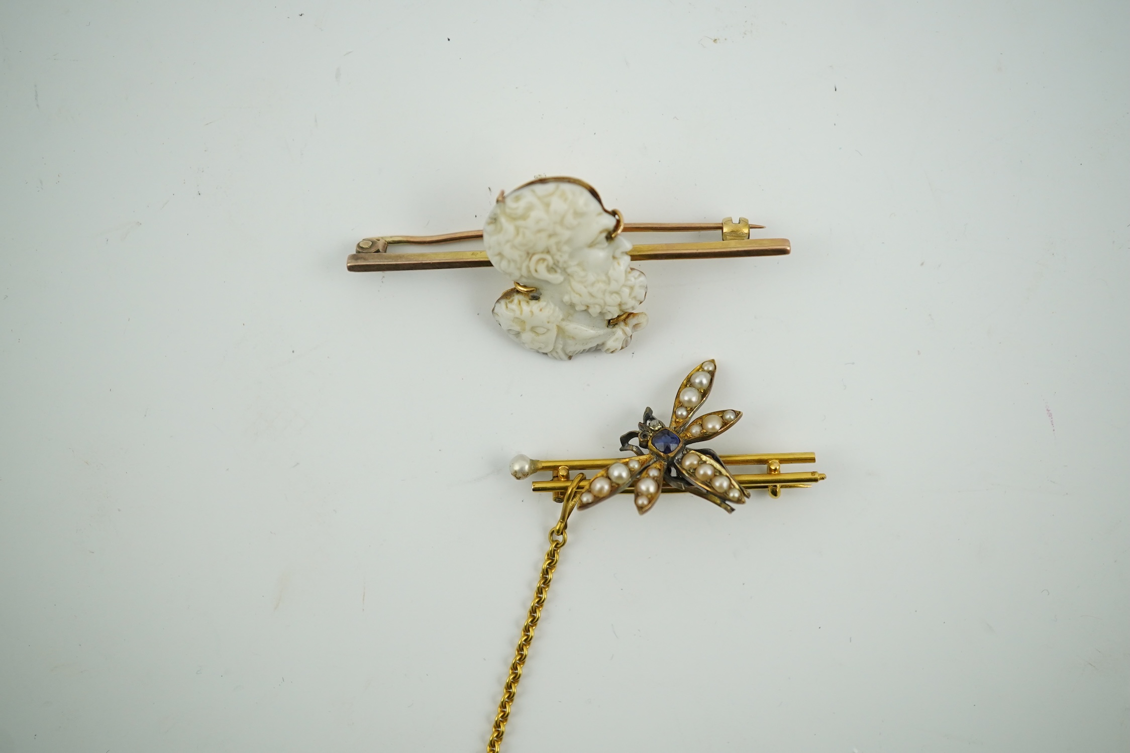 An Edwardian 15ct mounted cameo shell bar brooch, 49mm, together with a yellow metal, sapphire and split pearl cluster set dragonfly bar brooch, 11 grams. Condition - fair